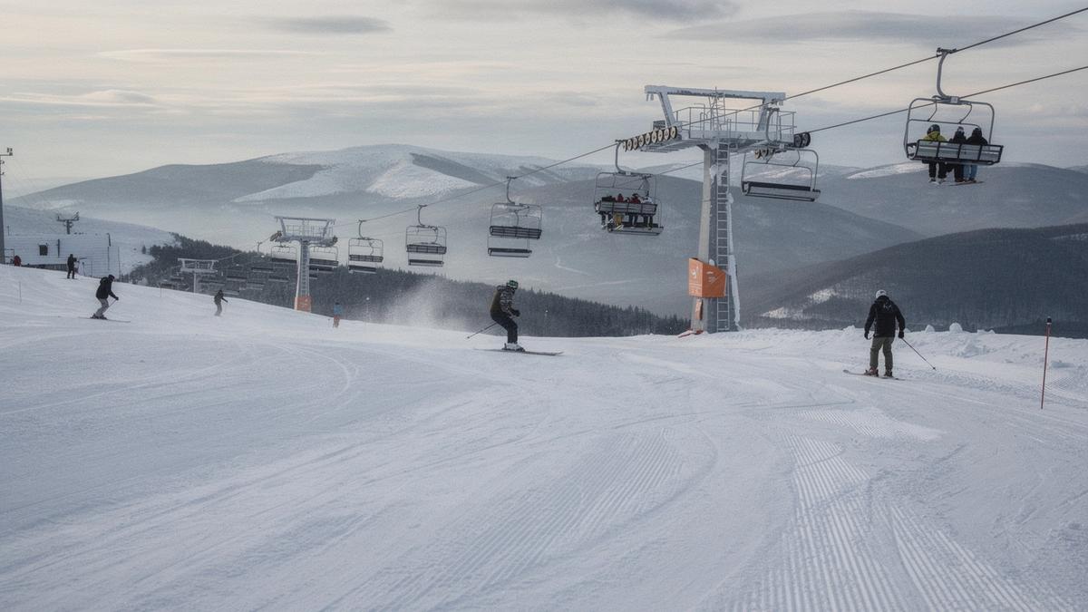 Chairlift and groomed pistes above the treeline on a clear winter morning